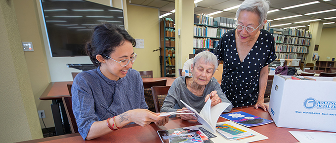 Visiting researcher Em Butler in the Annis Reading Room reviewing archival materials with Anne Frank and Christina Woo interim curator of the Southeast Asian Archive