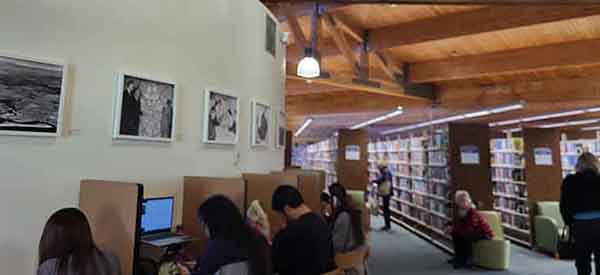 Special Collections photos on display in University Park Library branch above studying library users